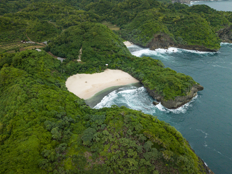 Aerial view of Sedahan Beach a golden sandy cove amidst green hills and turquoise waves Gunungkidul Regency Special Region of Yogyakarta Indonesia. Aerial view of Sedahan Beach a golden sandy cove amidst green hills and turquoise waves Gunungkidul Regency Special Region of Yogyakarta Indonesia.