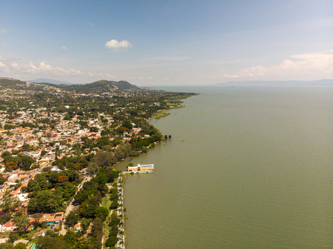 Aerial view of the town of Ajijic along the shore of Lake Chapala with lush trees and buildings under a clear blue sky in Ajijic Jalisco Mexico. Aerial view of the town of Ajijic along the shore of Lake Chapala with lush trees and buildings under a clear blue sky in Ajijic Jalisco Mexico.