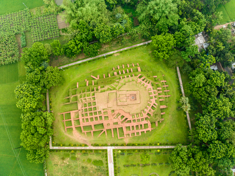 Aerial view of the ancient red brick foundations of the Gokul Medh archaeological site surrounded by lush green trees and rural fields in Bogura Rajshahi Division Bangladesh.