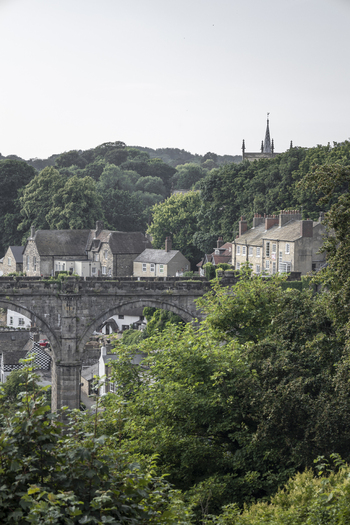 View of the historic Knaresborough Viaduct surrounded by lush green trees and stone buildings in Knaresborough England United Kingdom.