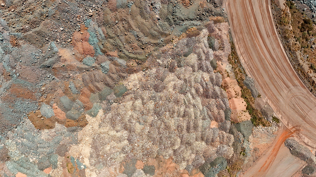 Aerial view of a rugged landscape revealing a striking mosaic of earthen tones and textures from excavated ground and a winding dirt road Rustenburg North West South Africa. Aerial view of a rugged landscape revealing a striking mosaic of earthen tones and textures from excavated ground and a winding dirt road Rustenburg North West South Africa.