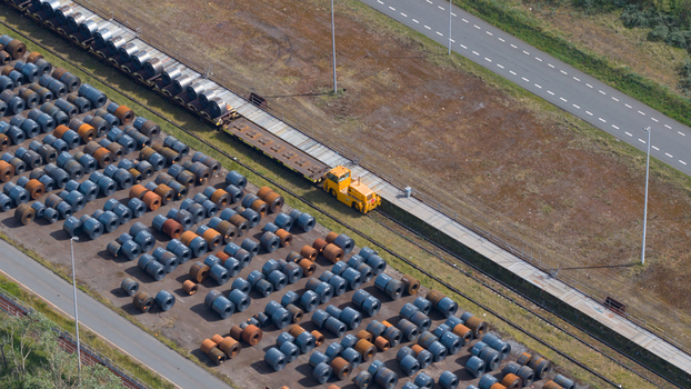Aerial view of the Tata Steel industrial site featuring rows of steel coils and a yellow transport vehicle on tracks in Velsen Noord Noord Holland Netherlands. Aerial view of the Tata Steel industrial site featuring rows of steel coils and a yellow transport vehicle on tracks in Velsen Noord Noord Holland Netherlands.