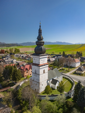Aerial view of the Church of Saint Matthew with its tall white bell tower and onion dome surrounded by village houses and green meadows in Partizanska Lupca Zilina Region Slovakia. Aerial view of the Church of Saint Matthew with its tall white bell tower and onion dome surrounded by village houses and green meadows in Partizanska Lupca Zilina Region Slovakia.