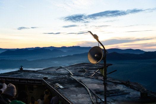 View of the summit area of Adam s Peak with a loudspeaker on a rooftop overlooking misty mountain ranges at sunrise in Ratnapura Sabaragamuwa Province Sri Lanka. View of the summit area of Adam s Peak with a loudspeaker on a rooftop overlooking misty mountain ranges at sunrise in Ratnapura Sabaragamuwa Province Sri Lanka.