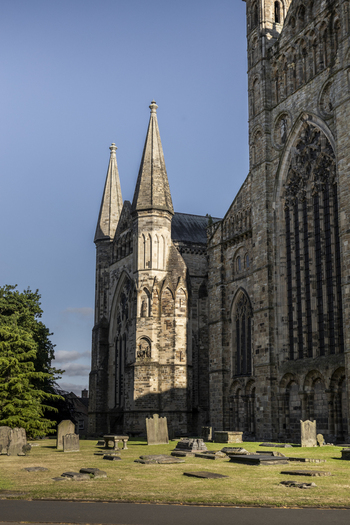 View of the historic Durham Cathedral with its gothic spires and stone architecture rising above a peaceful graveyard with ancient headstones and green grass in Durham England United Kingdom. View of the historic Durham Cathedral with its gothic spires and stone architecture rising above a peaceful graveyard with ancient headstones and green grass in Durham England United Kingdom.