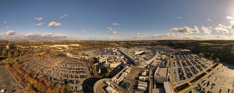 Aerial view of Bluewater Shopping Centre with its expansive parking lots curved architectural roof and surrounding green landscape in Dartford England United Kingdom. Aerial view of Bluewater Shopping Centre with its expansive parking lots curved architectural roof and surrounding green landscape in Dartford England United Kingdom.