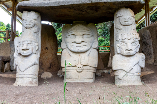 View of ancient stone statues at San Agustin Archaeological Park featuring intricate pre Columbian carvings under a protective wooden shelter in San Agustin Huila Colombia.
