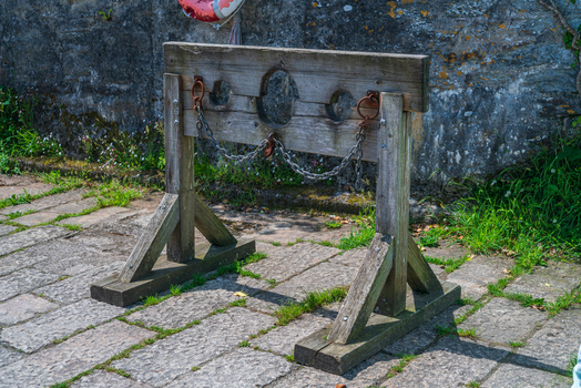View of a historic wooden pillory standing on stone paving in the coastal village of Charlestown Cornwall United Kingdom. View of a historic wooden pillory standing on stone paving in the coastal village of Charlestown Cornwall United Kingdom.
