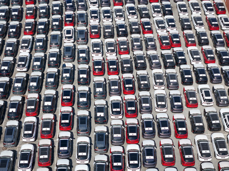 Aerial view of rows of new red and dark colored cars parked in an orderly fashion at a logistics terminal in Vado Ligure Liguria Italy.