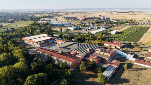 Aerial view of an industrial factory complex with large warehouses and red tiled roofs surrounded by agricultural fields and trees in Sremska Mitrovica Vojvodina Serbia. Aerial view of an industrial factory complex with large warehouses and red tiled roofs surrounded by agricultural fields and trees in Sremska Mitrovica Vojvodina Serbia.