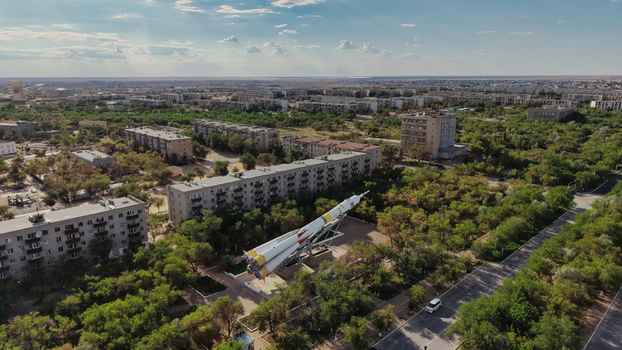 Aerial view of the Baikonur Cosmodrome rocket monument situated among residential apartment buildings and lush green trees in Karmakshy District Kyzylorda Region Kazakhstan.