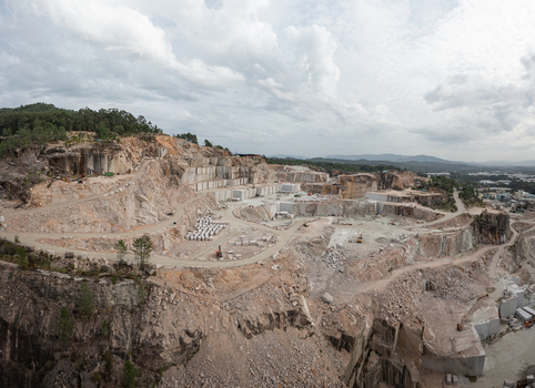 Aerial view of Cantera Porrino granite quarry showing large stone blocks excavation terraces and heavy machinery under a cloudy sky O Porrino Pontevedra Spain. Aerial view of Cantera Porrino granite quarry showing large stone blocks excavation terraces and heavy machinery under a cloudy sky O Porrino Pontevedra Spain.
