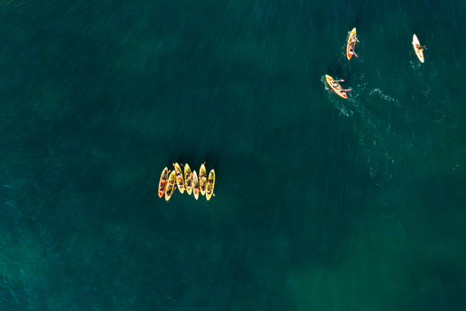 Aerial view of a group of people paddling in yellow kayaks on the clear blue water of the Atlantic Ocean in Lagos Faro District Portugal.