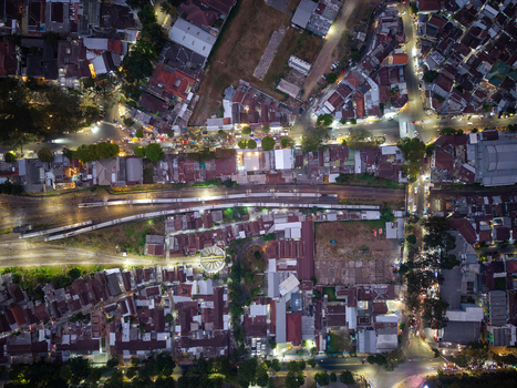 Aerial view of the city of Malang at night featuring illuminated streets dense residential rooftops and railway tracks running through the urban landscape in Malang East Java Indonesia.