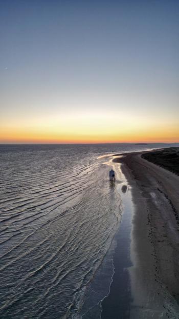 Aerial view of the iconic Burnham on Sea Low Lighthouse standing on the sandy beach during a vibrant sunset with calm waves gently lapping the shore in Burnham on Sea England United Kingdom. Aerial view of the iconic Burnham on Sea Low Lighthouse standing on the sandy beach during a vibrant sunset with calm waves gently lapping the shore in Burnham on Sea England United Kingdom.