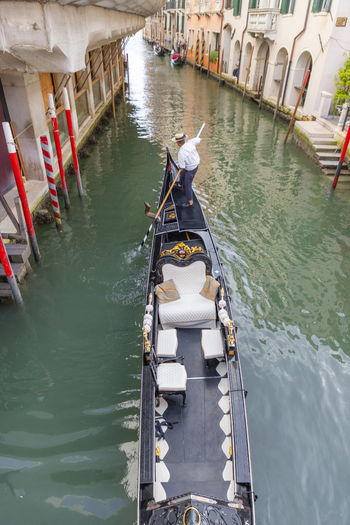 Venice Italy 21 September 2026 View of a gondolier steering a traditional black gondola through a narrow canal lined with historic buildings. Venice Italy 21 September 2026 View of a gondolier steering a traditional black gondola through a narrow canal lined with historic buildings.
