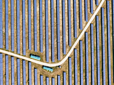 Aerial view of rows of blue solar panels in a large photovoltaic power plant with dirt access roads and utility buildings Torrazza Piemonte Piemonte Italy. Aerial view of rows of blue solar panels in a large photovoltaic power plant with dirt access roads and utility buildings Torrazza Piemonte Piemonte Italy.