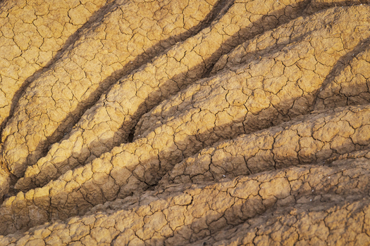 View of the cracked and eroded clay formations of Bardenas Reales with deep shadows and dry textures in Navarre Spain. View of the cracked and eroded clay formations of Bardenas Reales with deep shadows and dry textures in Navarre Spain.