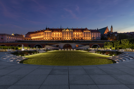 View of the illuminated Warsaw Royal Castle Gardens and the palace facade at dusk with manicured lawns and stone steps under a twilight sky Warsaw Masovian Voivodeship Poland. View of the illuminated Warsaw Royal Castle Gardens and the palace facade at dusk with manicured lawns and stone steps under a twilight sky Warsaw Masovian Voivodeship Poland.