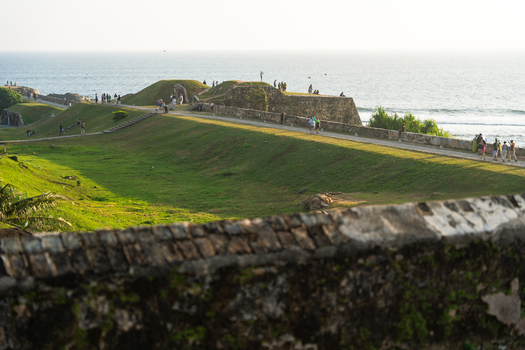 View of the historic Galle Fort ramparts with people walking along the stone walls and grassy slopes overlooking the ocean Galle Southern Province Sri Lanka.
