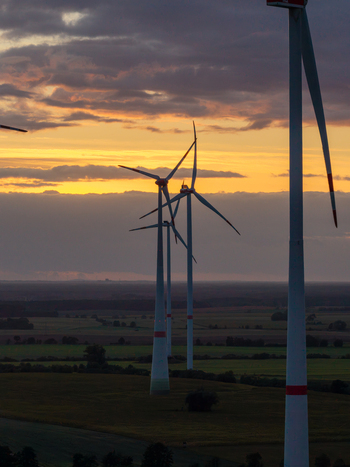 Aerial view of Sieversdorf Windpark with wind turbines standing in fields under a golden sunset sky in Jacobsdorf Brandenburg Germany. Aerial view of Sieversdorf Windpark with wind turbines standing in fields under a golden sunset sky in Jacobsdorf Brandenburg Germany.