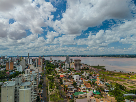 Aerial view of the urban skyline featuring residential buildings streets and the Parana River under a cloudy blue sky in Posadas Misiones Province Argentina. Aerial view of the urban skyline featuring residential buildings streets and the Parana River under a cloudy blue sky in Posadas Misiones Province Argentina.