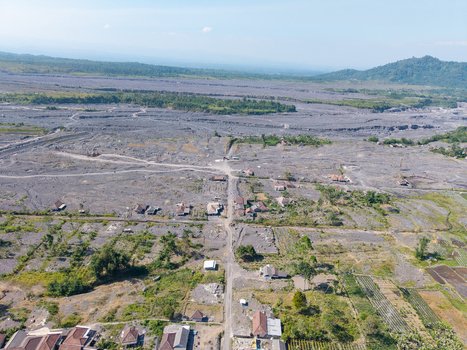 Aerial view of Supiturang Village showing the aftermath of the Mount Semeru volcanic eruption with volcanic ash covering the landscape and scattered houses in Pronojiwo East Java Indonesia.