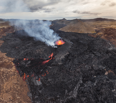 Aerial view of a volcanic eruption with glowing lava flows dark volcanic rock and smoke rising from the crater in Iceland. Aerial view of a volcanic eruption with glowing lava flows dark volcanic rock and smoke rising from the crater in Iceland.