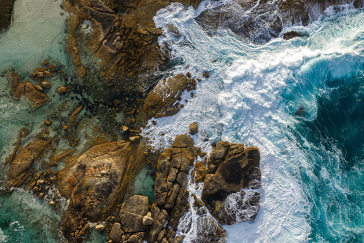 Aerial view of Two Peoples Bay Nature Reserve with rugged granite rocks and turquoise ocean waves crashing against the shore in Albany Western Australia Australia.