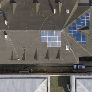 Aerial view of solar panels installed on a dark grey rooftop with triangular skylights and a parked car visible below in Istanbul Istanbul Turkiye.