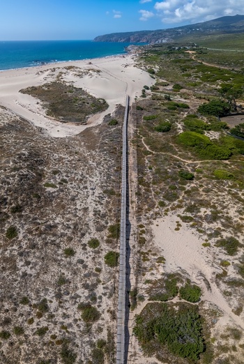 Aerial view of Praia do Guincho with its long wooden boardwalk leading to the sandy beach and the Atlantic Ocean in Cascais Lisbon Portugal. Aerial view of Praia do Guincho with its long wooden boardwalk leading to the sandy beach and the Atlantic Ocean in Cascais Lisbon Portugal.