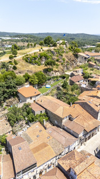 Aerial view of traditional stone houses with terracotta roofs a small garden with a blue swimming pool and a rocky hill in Allariz Province of Ourense Spain. Aerial view of traditional stone houses with terracotta roofs a small garden with a blue swimming pool and a rocky hill in Allariz Province of Ourense Spain.