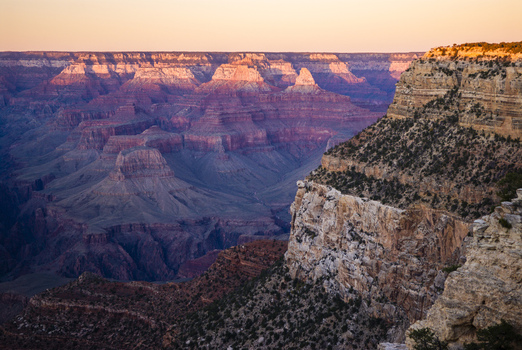 View of the Grand Canyon at sunset featuring layered rock formations deep shadows and golden light illuminating the canyon walls in Coconino County Arizona United States. View of the Grand Canyon at sunset featuring layered rock formations deep shadows and golden light illuminating the canyon walls in Coconino County Arizona United States.