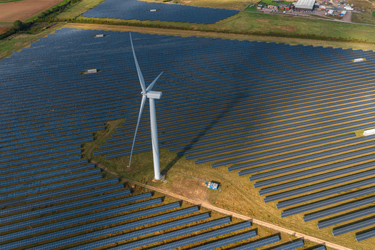 Aerial view of the Chelveston Renewable Energy site featuring a wind turbine surrounded by rows of solar panels and battery energy storage systems in Chelveston England United Kingdom. Aerial view of the Chelveston Renewable Energy site featuring a wind turbine surrounded by rows of solar panels and battery energy storage systems in Chelveston England United Kingdom.