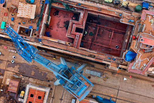 Pasai Donibane Spain 09 March 2026 Aerial view of Puerto Pasajes shipyard with a large blue crane and ship hull sections under construction in a dry dock. Pasai Donibane Spain 09 March 2026 Aerial view of Puerto Pasajes shipyard with a large blue crane and ship hull sections under construction in a dry dock.