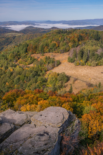 Aerial view of Sitno in Stiavnicke Vrchy with vibrant autumn foliage covering the rolling hills and a layer of morning mist in the distance Ilija Banska Bystrica Regio Slovakia.