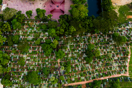 Aerial view of the dense rows of graves in Azimpur Graveyard surrounded by lush green trees and paved walkways in Dhaka Dhaka Division Bangladesh.