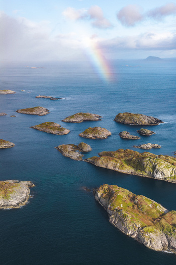 Aerial view of the rocky islets of the Lofoten archipelago in the Norwegian Sea with a rainbow appearing in the sky near Leknes Nordland Norway. Aerial view of the rocky islets of the Lofoten archipelago in the Norwegian Sea with a rainbow appearing in the sky near Leknes Nordland Norway.