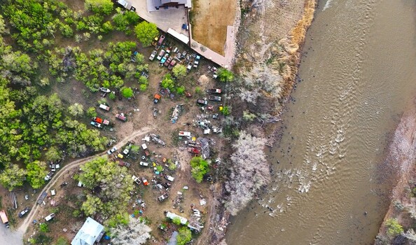 Aerial view of a collection of vehicles scattered amidst lush greenery alongside the winding river creating a vibrant contrast of nature and machine Palisade Colorado USA. Aerial view of a collection of vehicles scattered amidst lush greenery alongside the winding river creating a vibrant contrast of nature and machine Palisade Colorado USA.