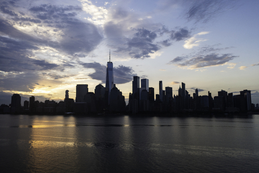 Aerial view of the New York skyline at sunset with the One World Trade Center rising above the city buildings and reflecting in the Hudson River New York New York United States.