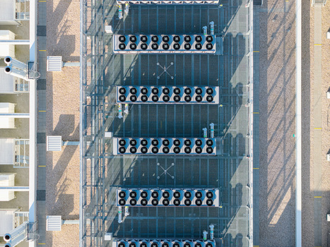 Aerial view of Vantage Data Centers BER1 featuring rows of industrial cooling fan units on the roof with gravel surfaces and shadows in Ludwigsfelde Brandenburg Germany. Aerial view of Vantage Data Centers BER1 featuring rows of industrial cooling fan units on the roof with gravel surfaces and shadows in Ludwigsfelde Brandenburg Germany.
