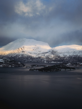 Aerial view of snow capped mountains meeting the dark waters with small islands scattered in between Sjøvegan Troms Norway. Aerial view of snow capped mountains meeting the dark waters with small islands scattered in between Sjøvegan Troms Norway.