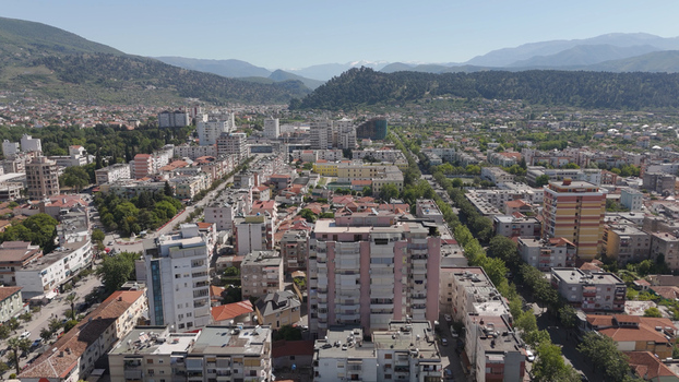 Aerial view of the urban landscape of Elbasan featuring residential buildings and streets surrounded by mountains in Elbasan Elbasan County Albania.