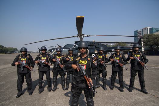 Dhaka Bangladesh 19 January 2017 View of Rapid Action Battalion RAB officers in black uniforms holding rifles in front of a helicopter at the RAB Headquarters. Dhaka Bangladesh 19 January 2017 View of Rapid Action Battalion RAB officers in black uniforms holding rifles in front of a helicopter at the RAB Headquarters.