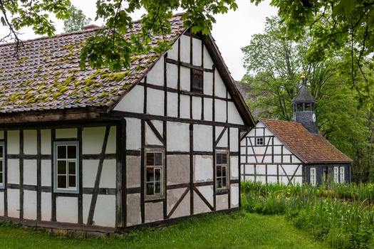 View of Hennebergisches Museum Kloster Vessra with traditional half timbered buildings moss covered roofs and lush green trees Kloster Vessra Thuringen Germany.