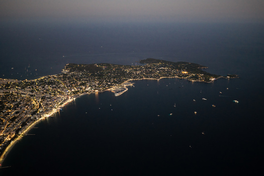 Aerial view of the illuminated coastline and harbor of Antibes at night featuring city lights reflecting on the Mediterranean Sea Antibes Provence Alpes Cote d Azur France. Aerial view of the illuminated coastline and harbor of Antibes at night featuring city lights reflecting on the Mediterranean Sea Antibes Provence Alpes Cote d Azur France.