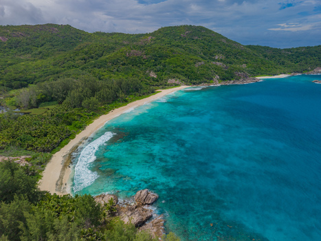 Aerial view of turquoise waters meet the white sands embraced by lush green hills creating a serene coastal panorama Police bay Mahe Island Seychelles. Aerial view of turquoise waters meet the white sands embraced by lush green hills creating a serene coastal panorama Police bay Mahe Island Seychelles.