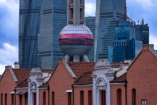 View of the Oriental Pearl Tower rising behind historic red brick buildings in the city center of Shanghai Shanghai China.