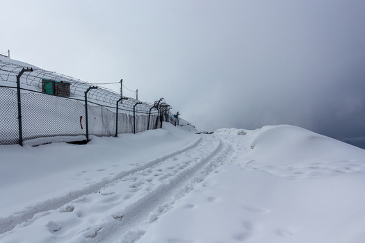 View of snow covered ground with tire tracks leading towards a fence under a cloudy sky Pir Chanasi Azad Kashmir Pakistan. View of snow covered ground with tire tracks leading towards a fence under a cloudy sky Pir Chanasi Azad Kashmir Pakistan.