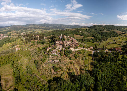 Aerial view of the historic hilltop village of Montefioralle surrounded by lush vineyards olive groves and rolling hills under a bright blue sky Montefioralle Tuscany Italy. Aerial view of the historic hilltop village of Montefioralle surrounded by lush vineyards olive groves and rolling hills under a bright blue sky Montefioralle Tuscany Italy.